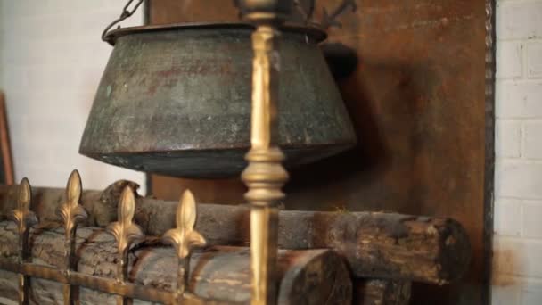 Mittelalterlicher Schornstein mit hängendem Metallkessel und Baumstämmen — Stockvideo