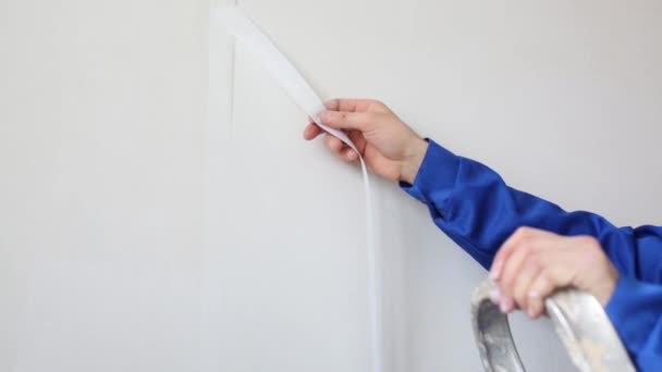 Werknemer verwijdert overtollige glasvezel, volgende man besteedt roller op muur — Stockvideo
