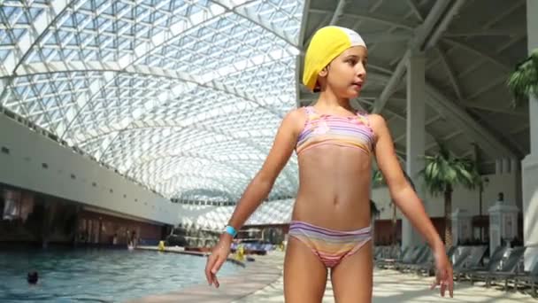 Menina fica perto da piscina interior — Vídeo de Stock