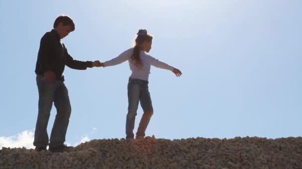 Mädchen und Junge bewegen sich auf Steinhaufen — Stockvideo