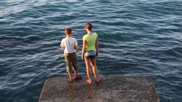 Niño con la madre peces en el mar en el muelle — Vídeos de Stock