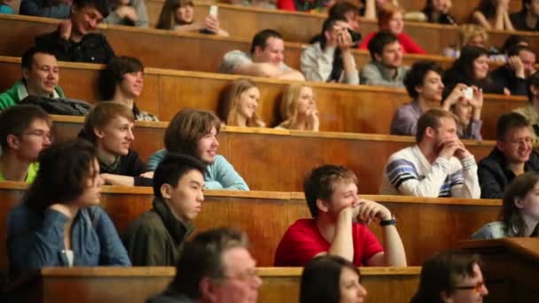 Estudiantes sonrientes se sientan en el auditorio — Vídeos de Stock