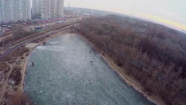 Люди катаются на коньках на ледяном пруду — стоковое видео