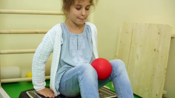 Маленька дівчинка сидить на вібраційній платформі — стокове відео
