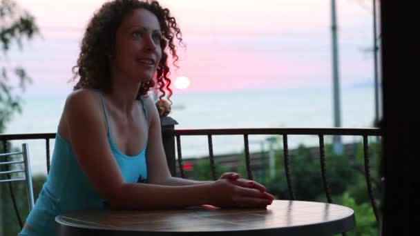 Mujer se sienta a la mesa en el balcón — Vídeos de Stock
