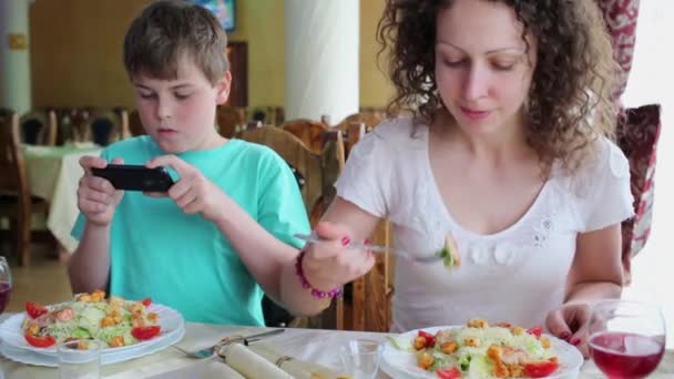 Madre e hijo se sientan a la mesa en la cafetería — Vídeos de Stock