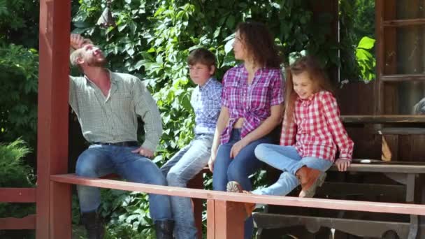 Family dressed like cowboys sits on veranda — Stock Video