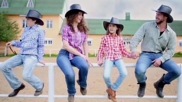 Cowboy family sits on fence against squat building — Stock Video