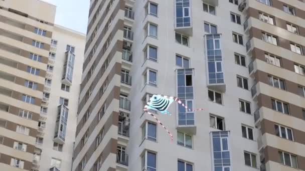 Striped kite flies against residential buildings — Stock Video