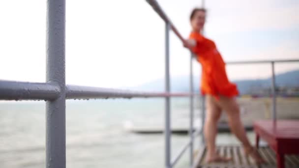 桟橋で金属フェンスの上に女性が傾いています。 — ストック動画