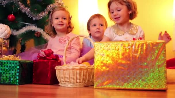 Kleine meisjes en jongen in de buurt van de kerstboom — Stockvideo