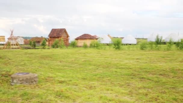 Old wooden houses at green field — Stock Video