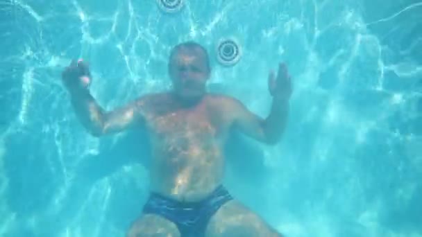 Man sits on bottom of pool underwater — Stock Video