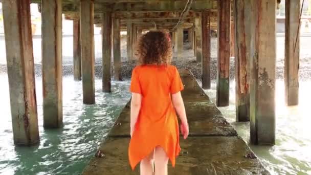 Mulher caminha sob estrutura de concreto — Vídeo de Stock