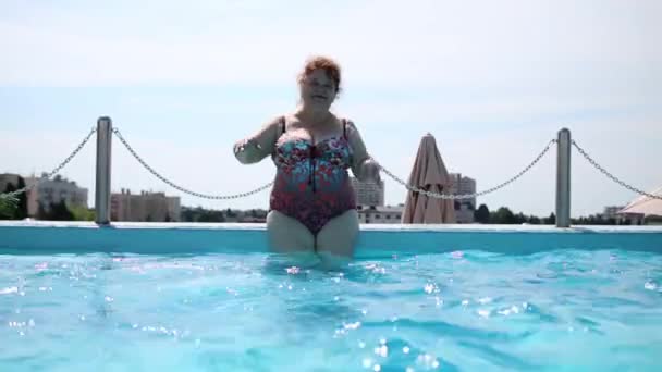 Ηλικιωμένη γυναίκα με μαγιό στέκεται στην πισίνα — Αρχείο Βίντεο