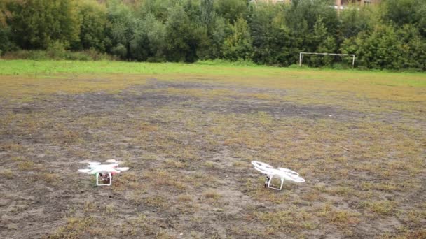 Two quadrocopters fly up from grass — Stock Video