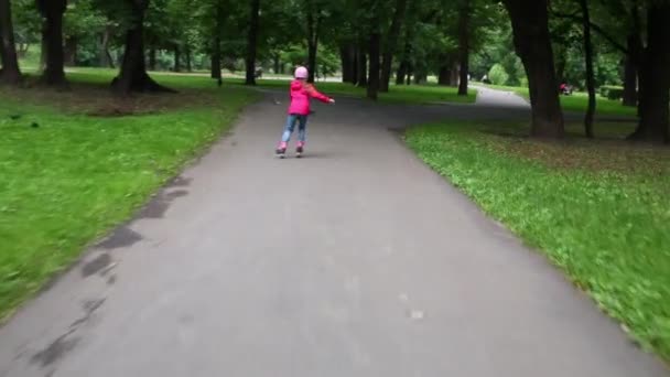 Achterkant meisje rolschaatsen in park — Stockvideo