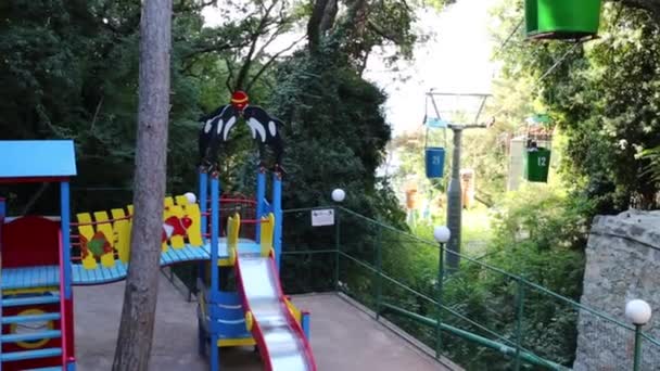 Teleférico entre árboles y parque infantil — Vídeos de Stock