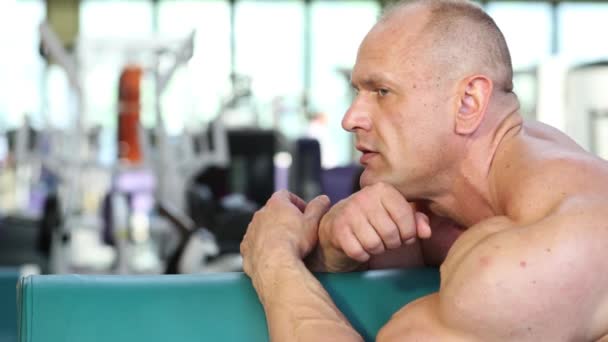 Tired bodybuilder strains muscles — Stock Video