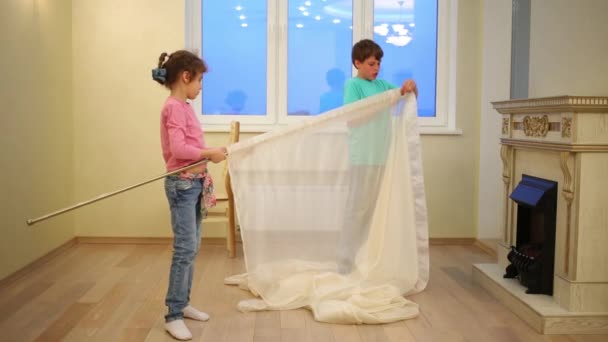 Brother and sister hanging curtains — Stock Video