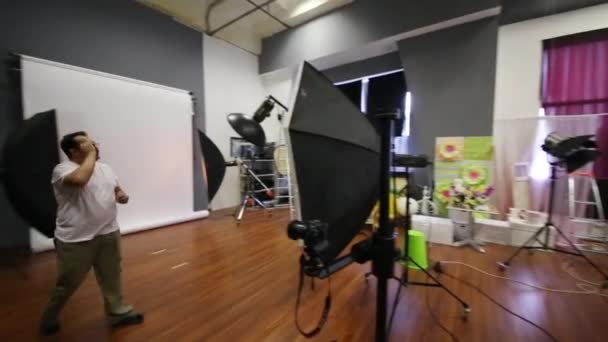 Man configures photographic equipment before shooting in studio