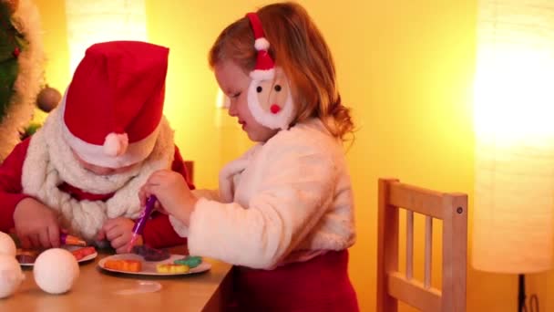 Barn måla cookies nära julgran — Stockvideo