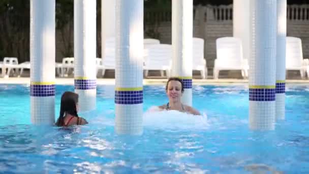 Lächelnde Frau und Mädchen schwimmen im Pool mit Whirlpool und Rotunde — Stockvideo