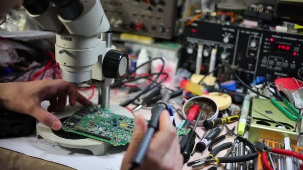 Man looks at motherboard through microscope and solders — Stock Video