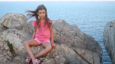 Güzel kız rock deniz kenarında oturur