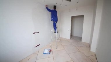 Duvara bir merdiven ve koyar fiberglas üzerinde duran işçi