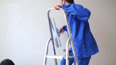 Bir adam merdivene koyar, o ve düzgünleştirir üzerinde fiberglas tırmanıyor
