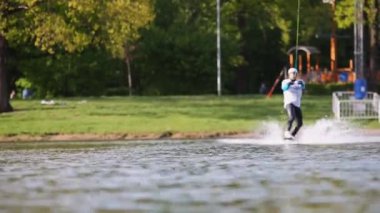 Erkek wakeboarder atlar ve gemide döner