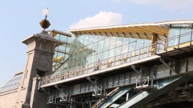 Şehirdeki cam duvarlı yaya köprüsü üzerinde giden adam