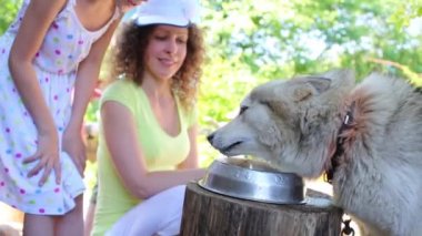 Woman and girl look at drinking dog 