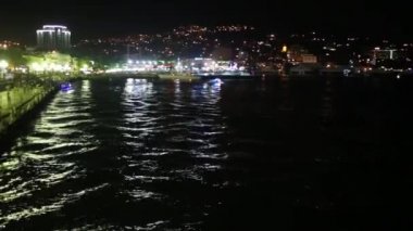 Deniz, dağ, dolgu ve insanlar gece görünümü