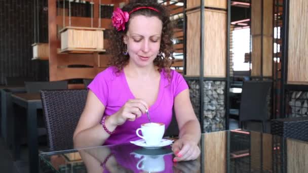 Женщина мешает кофе ложкой в кафе. — стоковое видео