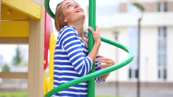 Smiling girl climbs up on pole — Stock Video