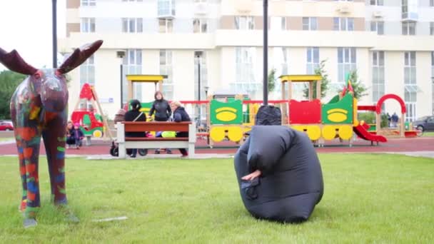 Girl in inflatable costume falls on grass — Stock Video