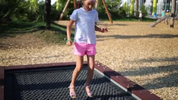 Menina pulando na grade no playground — Vídeo de Stock