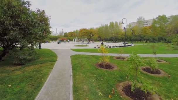 Menschen spazieren im Fliedergarten über den Platz — Stockvideo