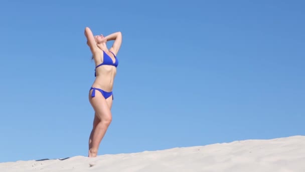 Žena v plavkách stojí na písku — Stock video