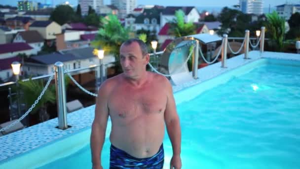 Oudere man duikt in blauwe zwembad — Stockvideo