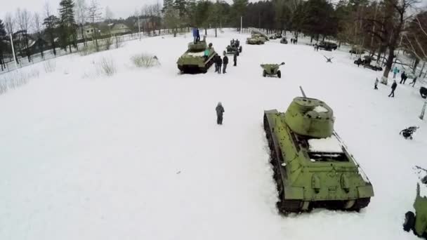 Människor går bland militär hårdvara — Stockvideo