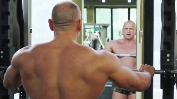 Bodybuilder hebt Gewichte in der Nähe des Spiegels — Stockvideo