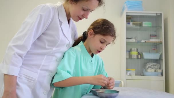 Chica y médico mirando en cuenco de metal — Vídeos de Stock