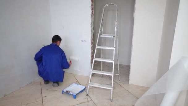 Squat operai e spalmi colla al muro con un rullo — Video Stock