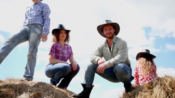 Cowboy family sits on dried hay bales at ranch — Stock Video