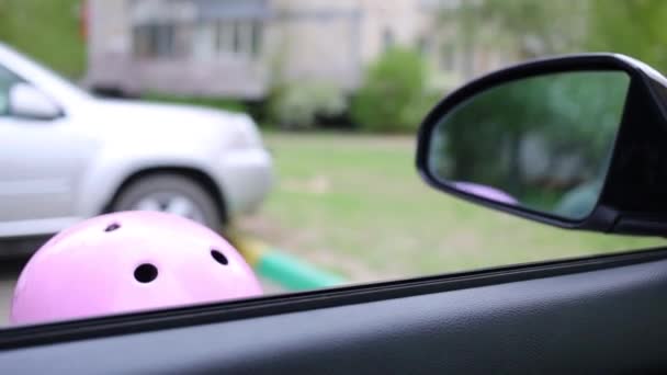 Girl in helmet hiding and looking into car — Stock Video