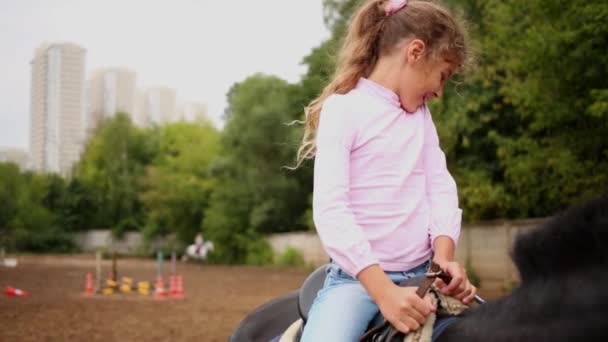 Маленька дівчинка сидить на темному коні — стокове відео