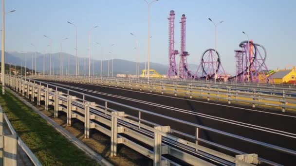 Coche se mueve en la carretera cerca del parque de atracciones — Vídeos de Stock